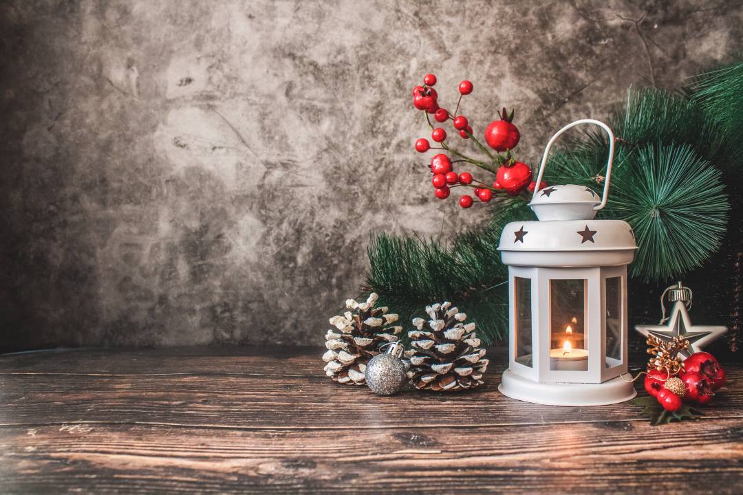 Lit candle, pine cones, and Christmas decorations placed on a table top