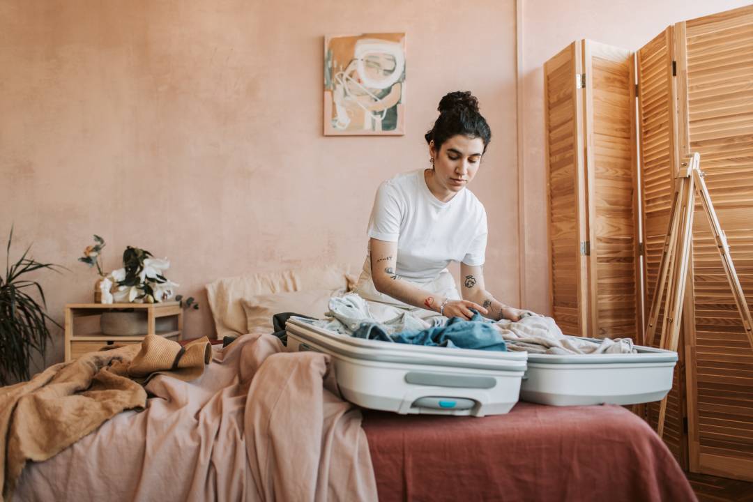 Woman Packing A Suitcase On A Bed