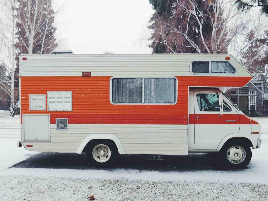 White RV With Red Stripe Parked On A Snowy Road