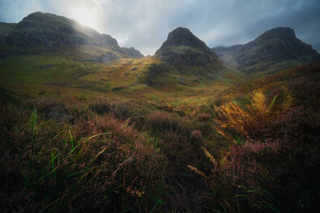 Three Sisters Of Glen Coe With Dark Cloudy Background
